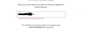 A student looking at a laptop while holding a university ID card.